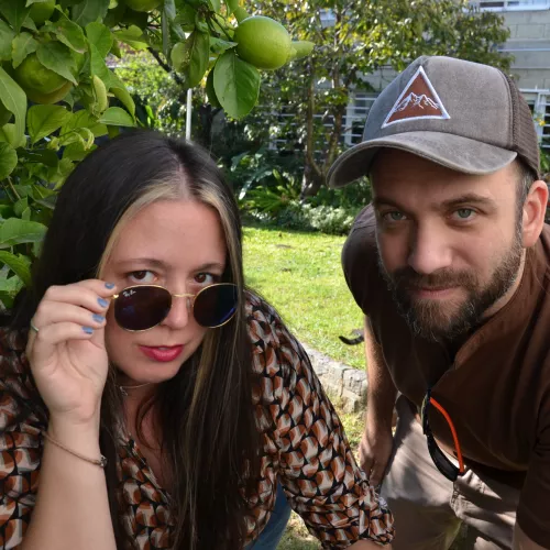 en un jardín, con un limonero y pasto de fondo, laura y gabriel miran a cámara.