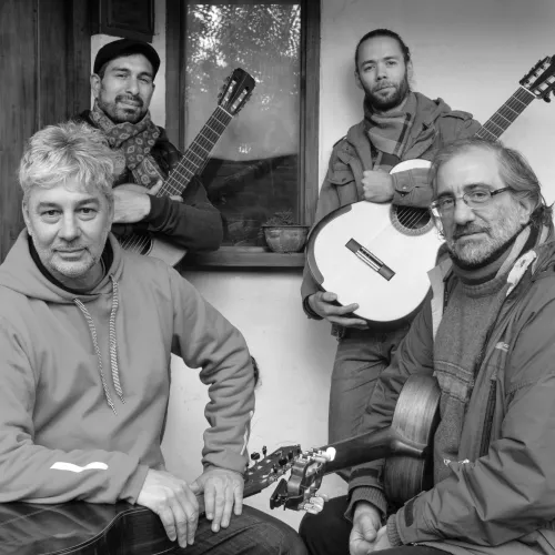 cuatro guitarristas posando sonriendo y sosteniendo sus guitarras