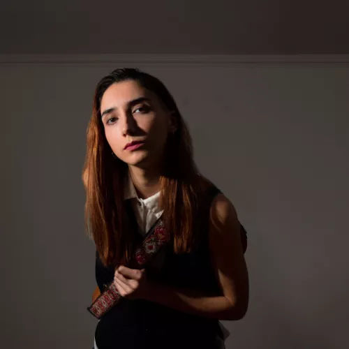 Luna Cabutti se acerca a cámara con su guitarra colgada
