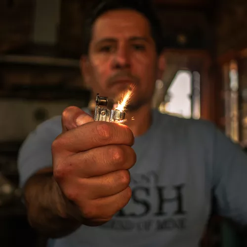 Imagen de frente del artista sosteniendo un encendedor