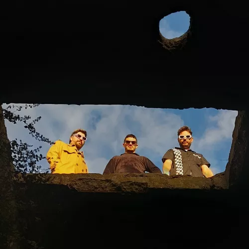 Los tres integrantes siendo fotografiados desde abajo. 