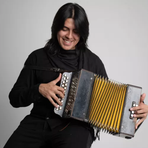Santiago Torres tocando un acordeón, con ropa de color negra