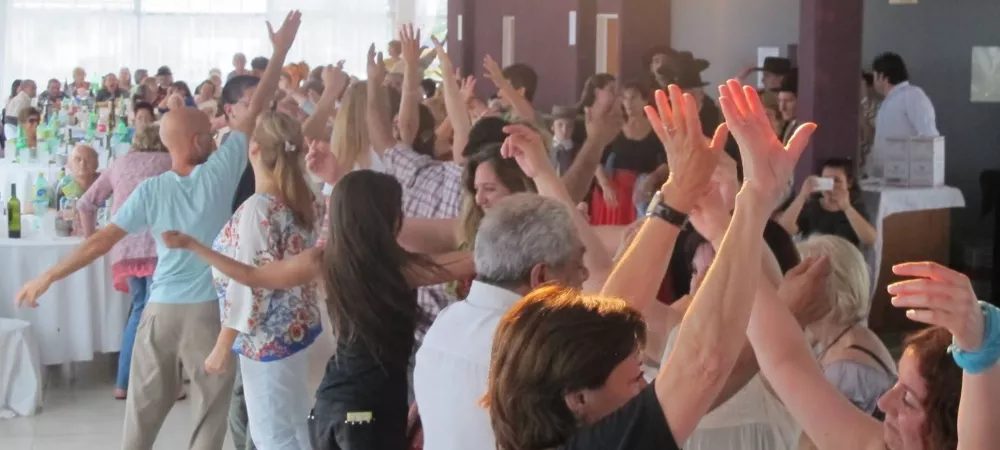 Evento / participación:  Público participando de una actividad cultural y recreativa en un espacio cerrado, con personas bailando y compartiendo el encuentro.