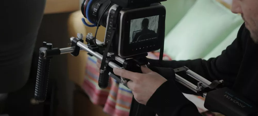 Producción audiovisual:  Persona operando una cámara profesional durante una producción audiovisual.