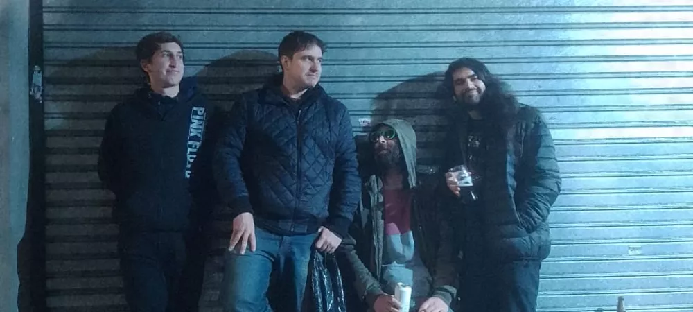 cuatro integrantes de la banda parados adelante de una persiana y arriba de ellos dice "Modern Men"