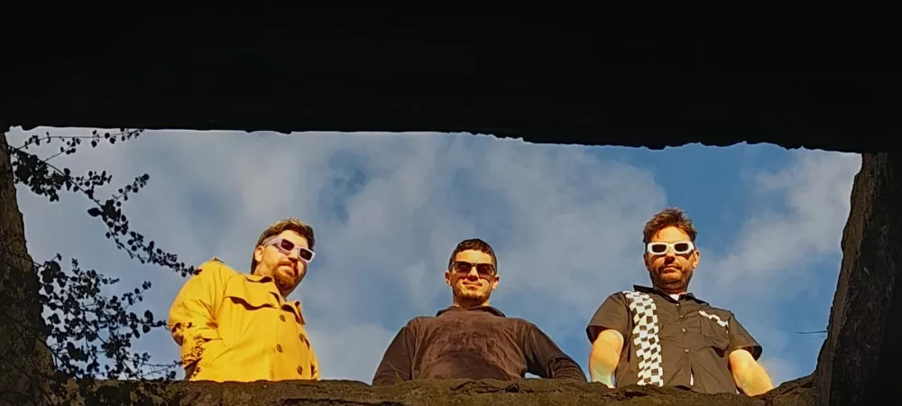 Los tres integrantes siendo fotografiados desde abajo. 