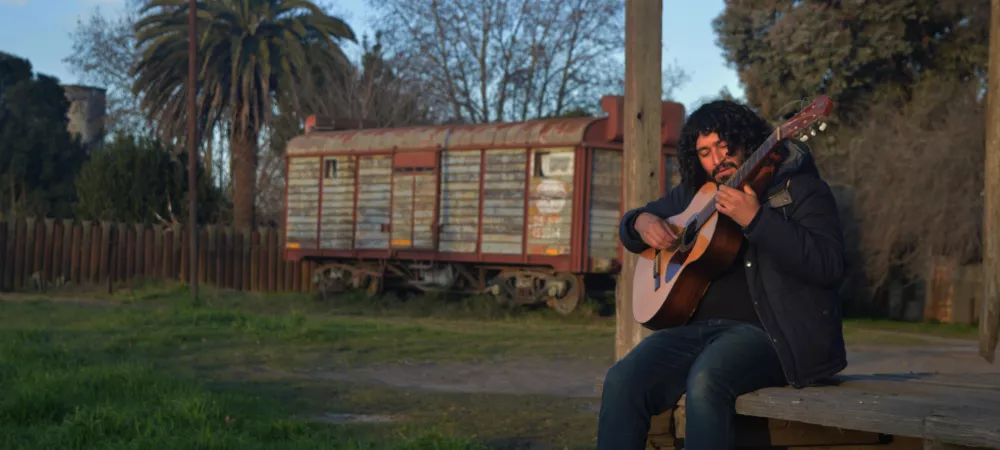 Hombre tocando la guitarra en anden