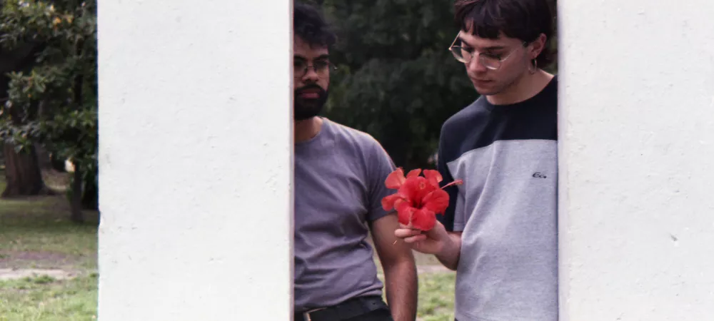 Dos personas paradas, una sosteniendo una rosa china