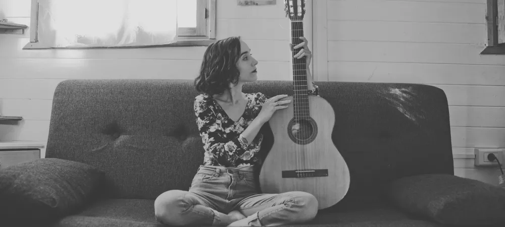 Caro Vitali sentada con su guitarra