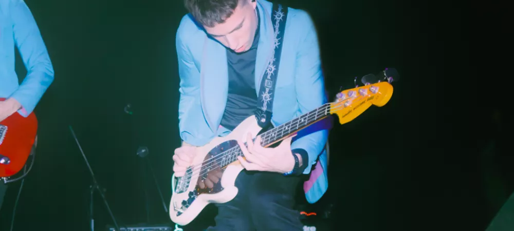 WALDEMAR, BAJISTA, CON UN BAJO COLOR BLANCO AGACHADO EN EL ESCENARIO DE UN SHOW