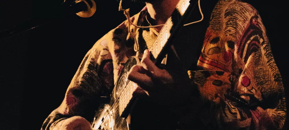 un hombre con un kazoo en la boca, tocando una guitarra de metal