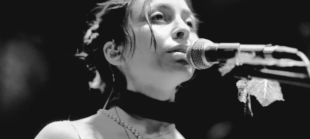 Imagen en blanco y negro de mujer joven con el pelo recogido cantando