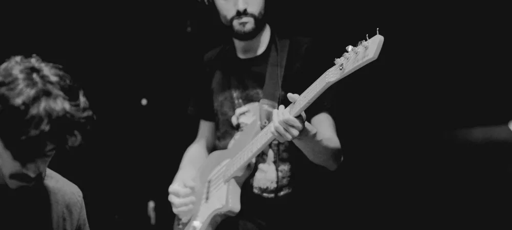 Imagen en blanco y negro que muestra a un hombre joven tocando el bajo
