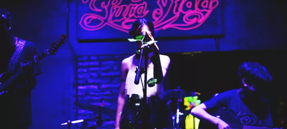 Imagen de una banda tocando con un cartel de neón de fondo que dice Pura Vida