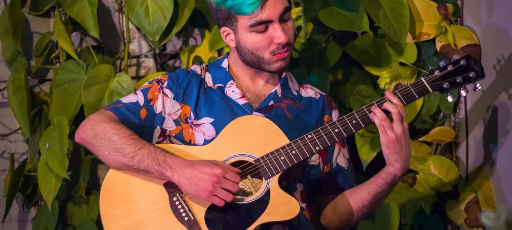 Tocando la guitarra con fondo de hojas. 