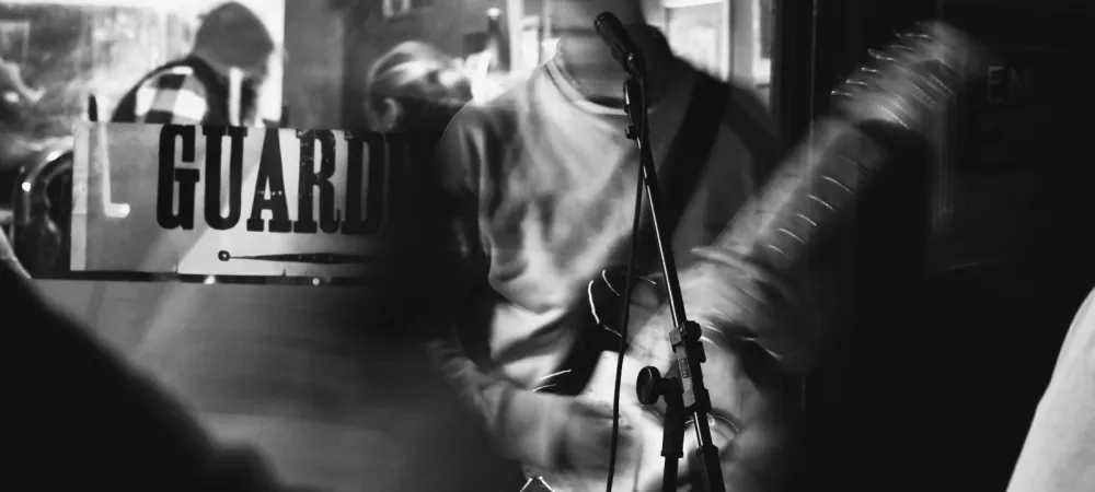 El músico tocando en la calle en una imagen borrosa y difuminada en blanco y negro, él está con su guitarra