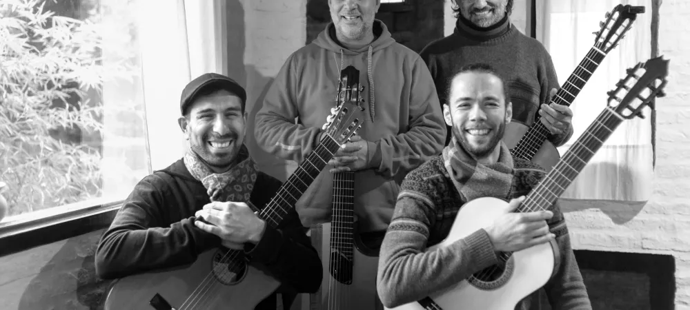 cuatro guitarristas posando sonriendo y sosteniendo sus guitarras