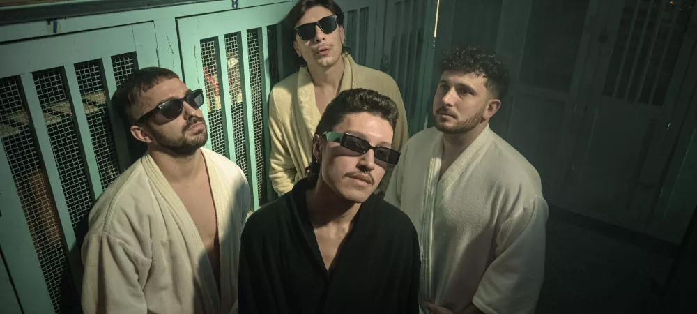 Foto horizontal de integrantes de la banda en vestuario con batas