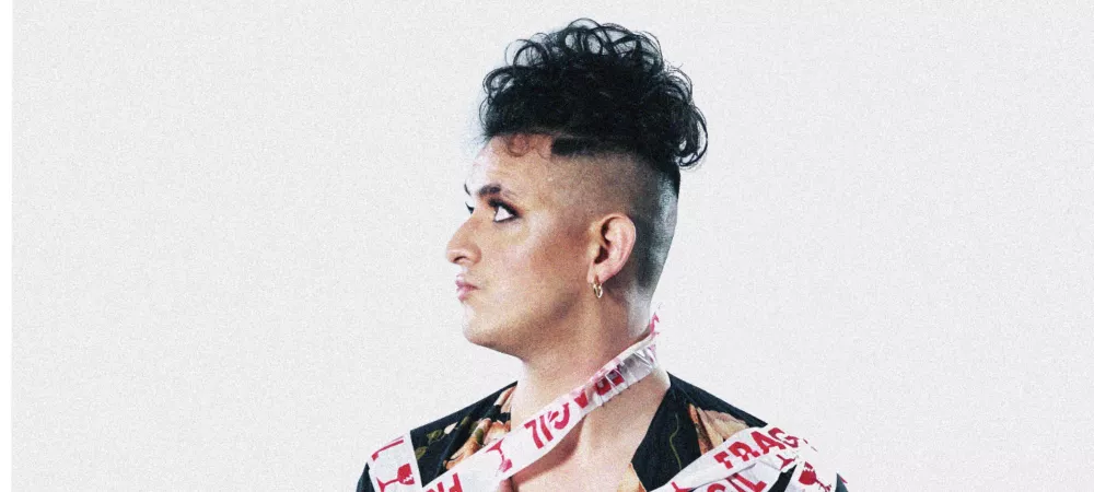 Fondo blanco, artista envuelto en cintas de frágil.