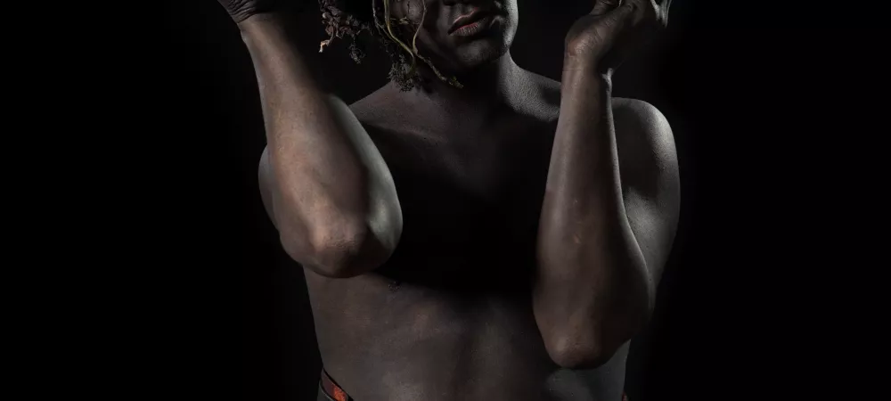 Artista con un maquillaje especial, el todo desnudo y el cuerpo pintado de negro. Findo negro