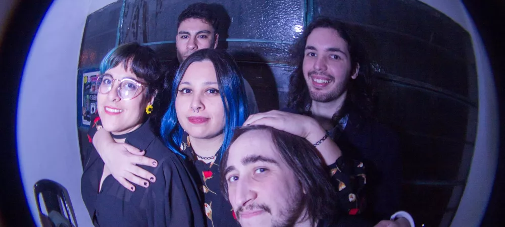 Un grupo de 2 chicas y 3 chicos abrazandose en el camarin de un recital