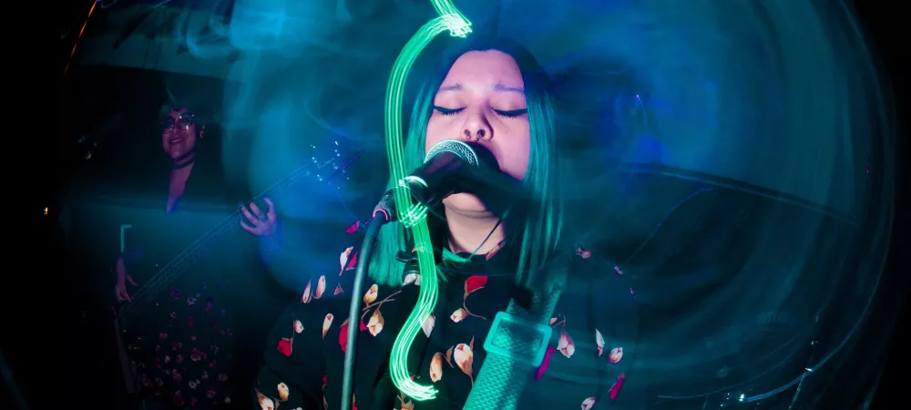 Una chica con los ojos cerrados cantando y tocando la guitarra en un escenario