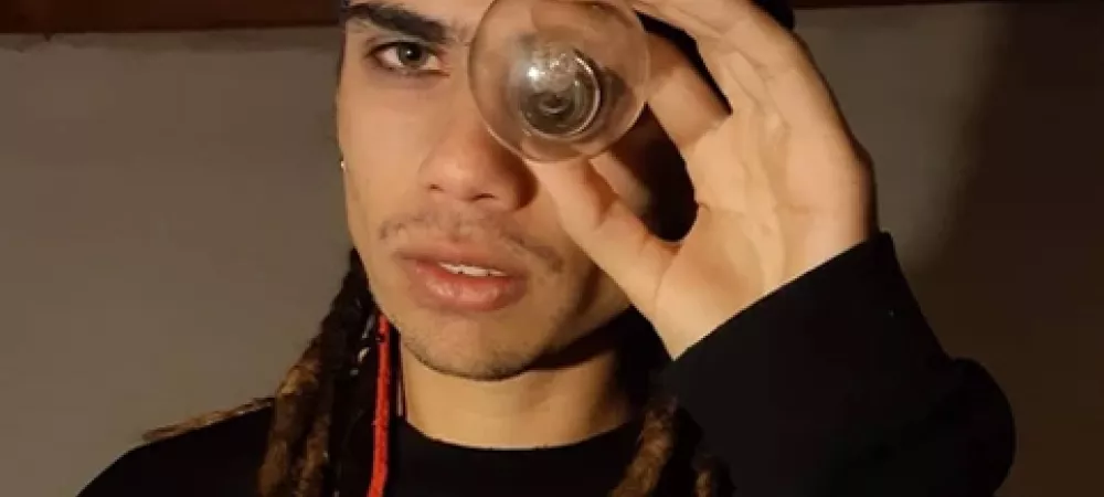 Keke NDK con rastas y una bandana en la cabeza, mirando a través de un foco