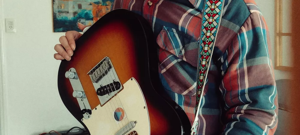 foto plano americano sosteniendo guitarra eléctrica.