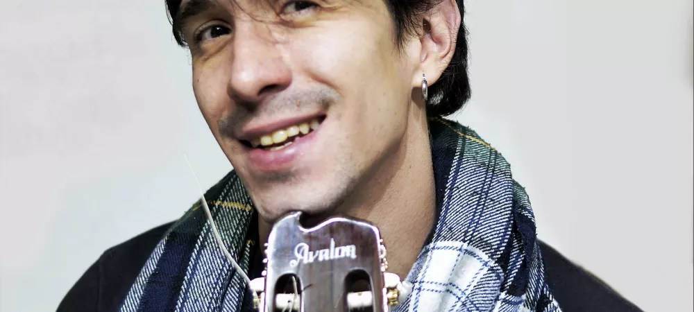 foto plano medio corto sosteniendo guitarra acústica.