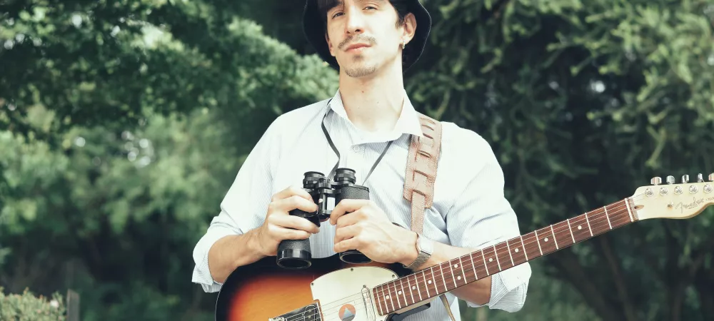foto plano medio en espacio verde sosteniendo guitarra eléctrica.