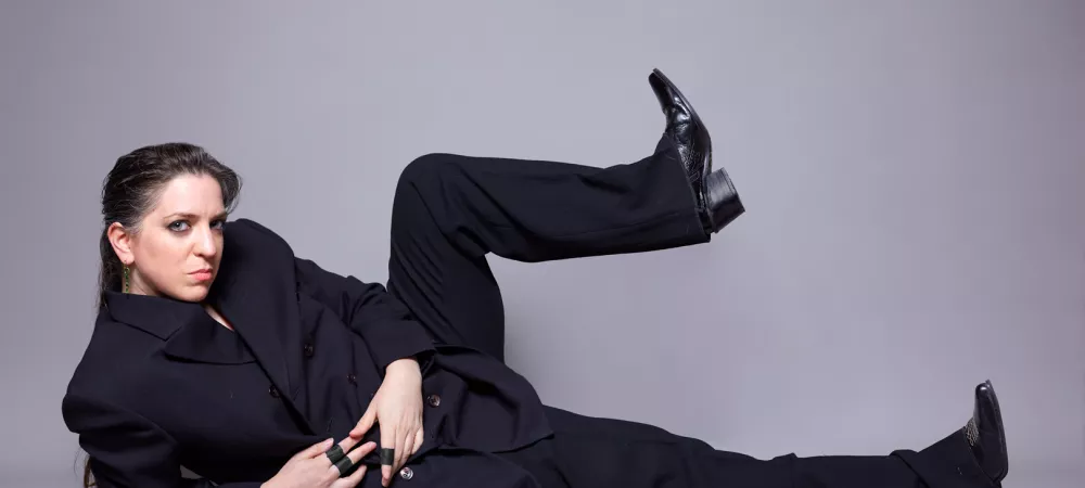 Lucy recostada con traje negro y gesto serio