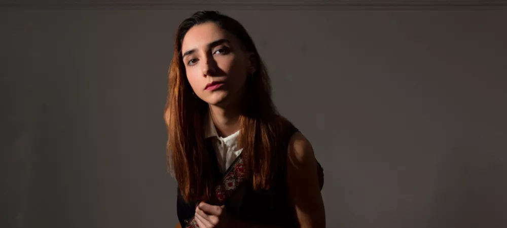 Luna Cabutti se acerca a la cámara con su guitarra colgada