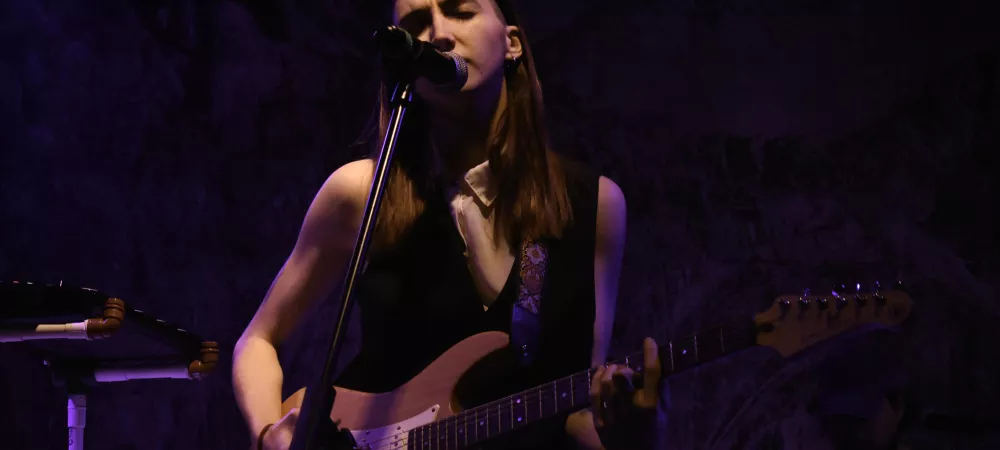 Luna Cabutti interpretando en vivo, con su guitarra cantando
