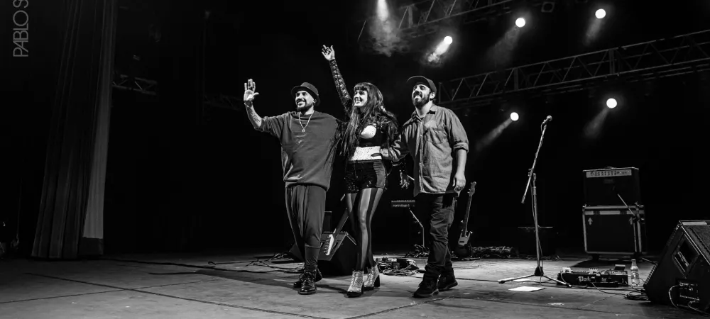 El trio saludando en un escenario