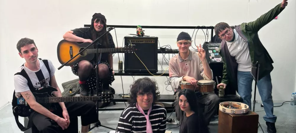 imágen de integrantes de la banda bajo una pancarta que dice "siempre quiero sentir"