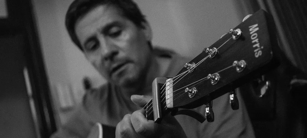 Foto en Blanco y negro del artista tocando una guitarra acústica.