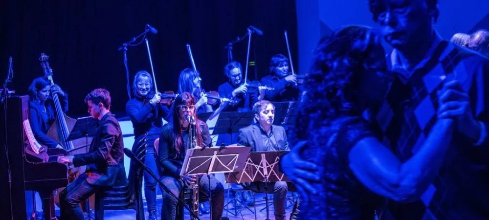 La orquesta en acción en La Milonga Vuelve al Barrio, tocando en la pista junto a lxs bailarines