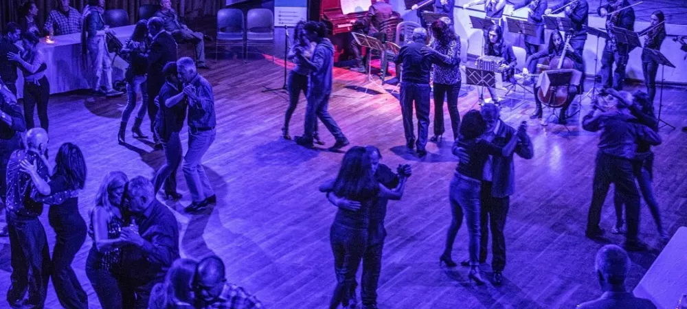 La orquesta en acción en La Milonga Vuelve al Barrio, tocando en la pista junto a lxs bailarines