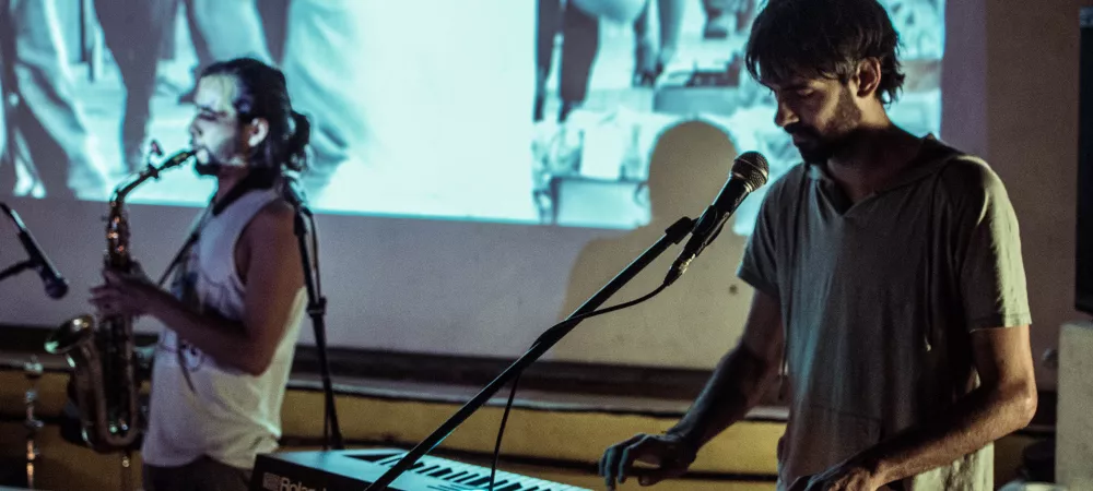 Foto de la banda tocando en vivo sobre proyección de cine mudo