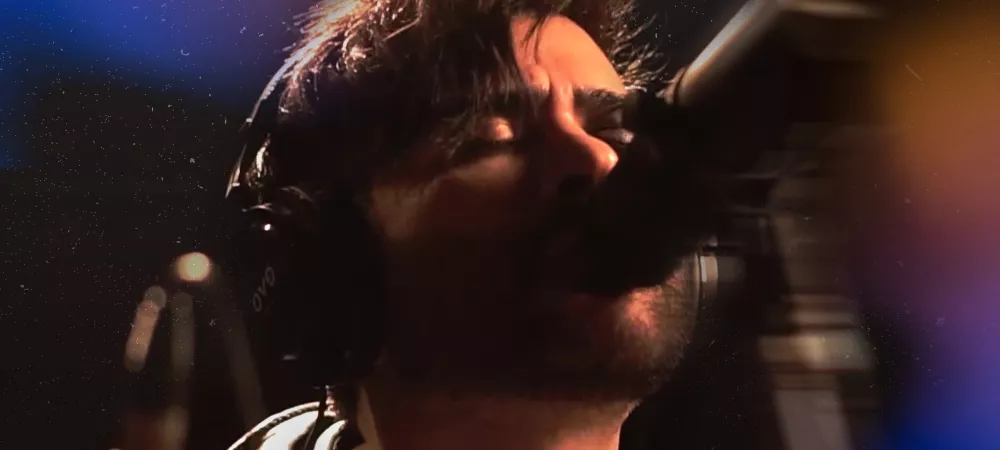 Artista Robyn Lekker cantando en un estudio de grabación con micrófono y auriculares, bajo iluminación artística.