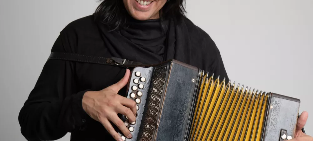 Santiago Torres tocando un acordeón, con ropa de color negra 